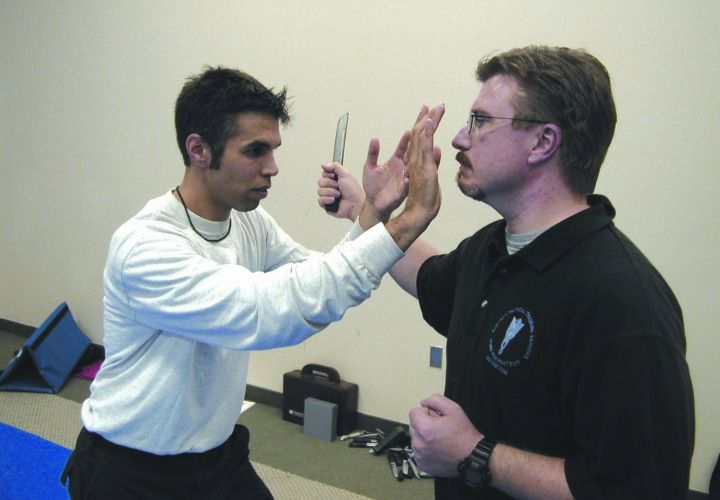 The author (left) demonstrates his technique for blocking a knife swipe while also going on the attack. Note that the block technique guards the most vulnerable arteries on the inside of the wrist and arm against the knife attack.