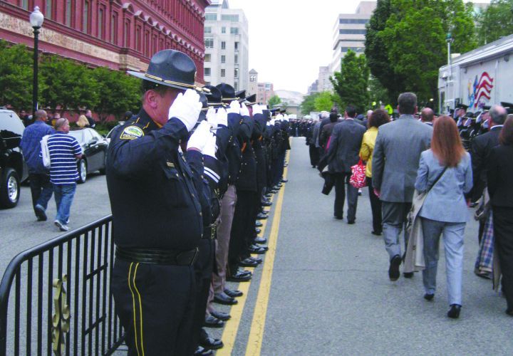 A block-long honor guard from agencies nationwide salutes police survivors arriving for the candlelight vigil during Police Week in Washington DC.