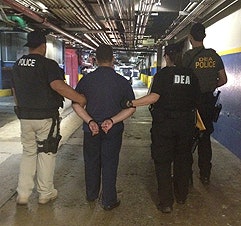 DEA agents escort an in-custody prisoner. Photo courtesy of DEA.