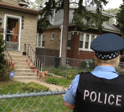 This dog is behind a fence, which is good. Now to keep it safe, the owner should call it into the house until the officer has left. (Photo: National Canine Research Council)