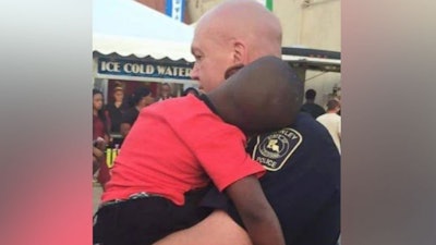 Officer David Taylor holds a lost child at last weekend's International Rice Festival in Crowley, LA. The boy was quickly reunited with his mother. (Photo: Facebook)