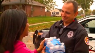 Urbandale, IA, woman gives bottled water to an Urbandale officer. Both the officer and the woman teared up as they talked. (Photo: KCCI TV screen shot)