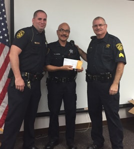 Deputy Edgardo Lucero receiving his 15-year service pin from his supervisors during his last night at work.