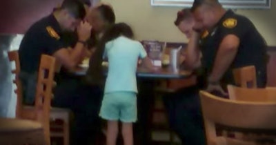8-year-old Paige Vazquez prays with San Antonio officers at a local restaurant. (Photo: YouTube Screenshot)