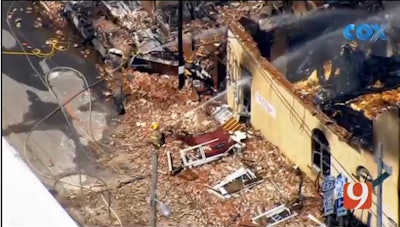 Firefighter sprays down the ruins of a home in Talihina, OK. The home burned after a booby trap exploded while law enforcement tried to serve a warrant to the resident. Four officers were injured in the explosion; the gunman was killed in a shootout with offficers. (Photo: News9 Screen Shot)
