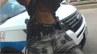 Screen grab of video footage that appears to show Harith Augustus move his hand toward his waistband and appears to show a gun and magazine tucked into his pants.