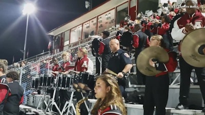 Screen grab of a video of Corporal Les Munn of the Texarkana (AR) Police Department playing along with a high school band's drumline.