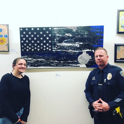 Student artist Alanna Rodriguez stands with School Resource Officer Mitch Brouillette of the Brentwood (CA) Police Department. Behind them is the painting she created and gave to the SRO with whom she has built a friendship.