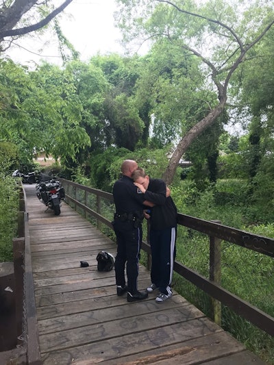 The agency posted an image of the embrace on Facebook, with the caption, 'Motor Officer Justin Thompson is really feeling the love today after locating a missing resident on the creek path.'