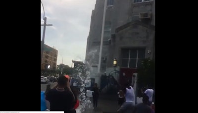 Screen grab of video posted to social media of a large group of young people in the Bronx approaching two female police officers on a sidewalk and dousing them with water.