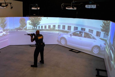 An officer trains using a FATS 300 multi-screen immersive simulator.