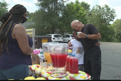 An officer with the South Bend (IN) Police Department was seen over the weekend helping two boys—a 12-year-old and his four-year-old brother—serving refreshments of lemonade, punch, and popcorn to area residents.