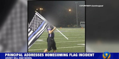 A football player at Charlotte's Ardrey Kell High School carried a Blue Lives Matter flag to honor the school's fallen SRO Friday night. (Photo: WSOC screen shot)