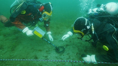 Divers use a Pulse 8X metal detector underwater.
