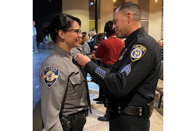 Sgt. Jeff Valdivia of the Escondido Police Department pins a deputy badge on Natalie Young. Valdivia rescued her from neglect in 2000. (Photo: Escondido PD)