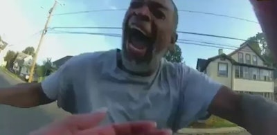 A still from a body camera video shows Winston Tate charging toward Detective Karli Travis wielding a hammer and yelling at the officer.