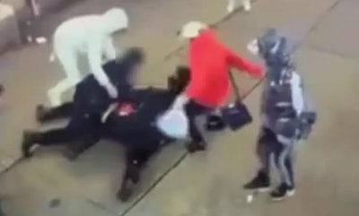 Still from NYPD video shows migrants kicking NYPD officers after they were knocked to the sidewalk Saturday, authorities say.