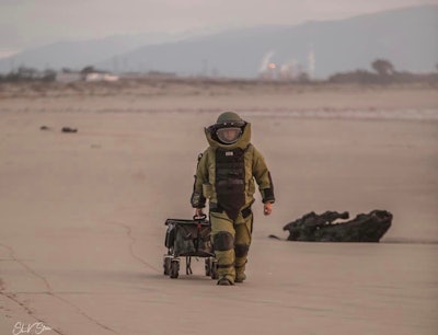 Bomb tech from the Santa Cruz County (California) Sheriff's Office approached a military bomb that washed up on the beach Sunday.