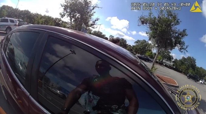 Flagler County Sheriff's Deputy Christian Harrison prepares to break a car window and rescue a trapped toddler from the heat of a Florida parking lot.