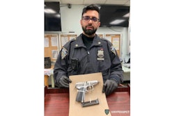 Officer Sumit Sulan holding the suspect's weapon in 2022. He has since been promoted to detective.