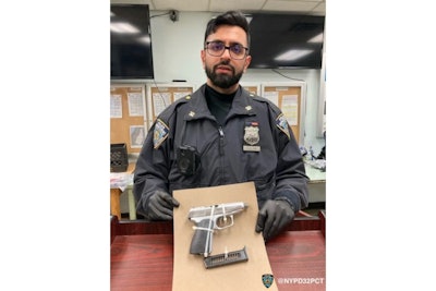 Officer Sumit Sulan holding the suspect's weapon in 2022. He has since been promoted to detective.