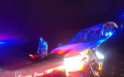 A Minnesota State Patrol trooper inspects the damage from the Honda SUV running into the back of Trooper Zach Gruver's Charger.