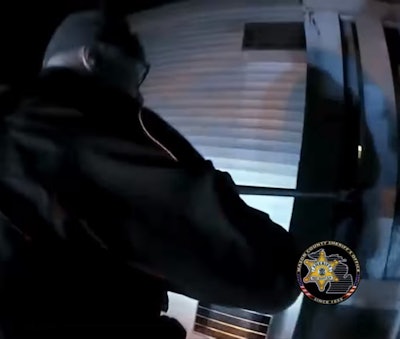 Sergeant Adam Claveau of the Mason County (Michigan) Sheriff's Office stands on the cab roof of his agency pickup and uses a crowbar to break off barriers on the balconies of apartments so that people can be rescued from a Monday fire.